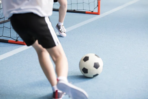 一个男孩和他的朋友在体育馆里玩足球的特写 — 图库照片
