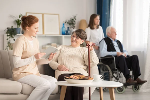Krankenschwester liest Senioren vor — Stockfoto