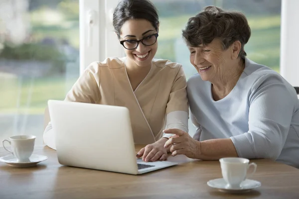 Smiling assistant teaching elderly woman