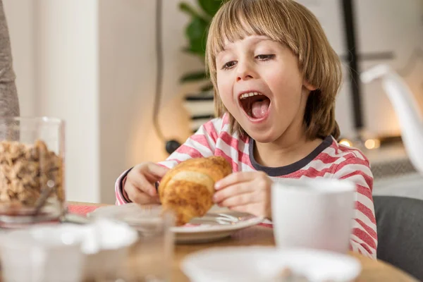 Jonge jongen eten croissant — Stockfoto