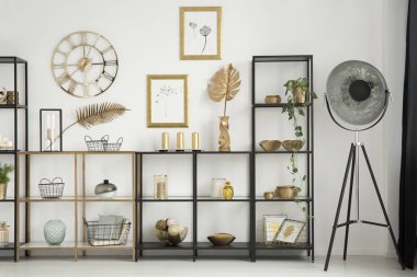 Raflar ile oturma odası iç yuvarlak masa saati duvara altın yapraklarla yanında endüstriyel lamba