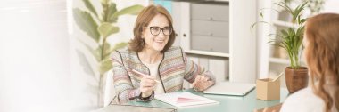 Gülümseyen, deneyimli kadın hastasını tedavi sırasında konuşurken Danışmanı