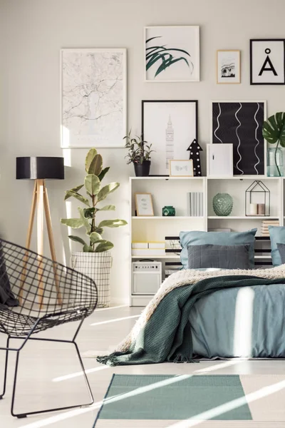 Sillón Junto Cama Con Manta Verde Contra Estantes Carteles Pared — Foto de Stock