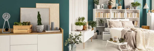 新鲜盆栽植物放在绿色开放空间卧室内部与双人床 书籍白色架子和现代绘画 — 图库照片
