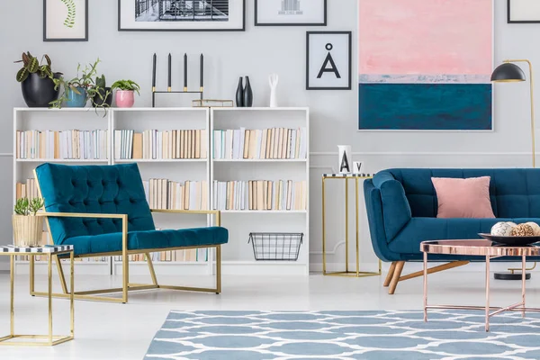 海军蓝色扶手椅反对书架在客厅内部与沙发和铜桌 — 图库照片
