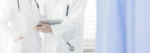 白色大衣的医生特写用听诊器拿着一块药片 在明亮的医院里与同事商量一下情况 — 图库照片