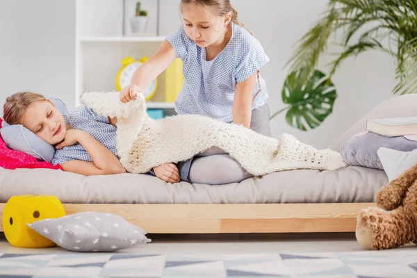 Doente Menina Deitada Cama Sua Irmã Cobrindo Com Cobertor — Fotografia de Stock