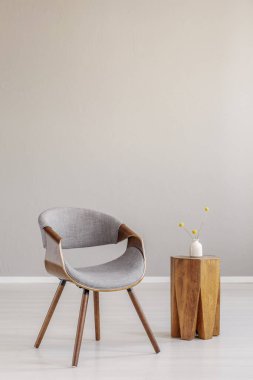 Boş oturma odasındaki şık, gri ahşap sandalye. Moda olan ahşap kahve masası.