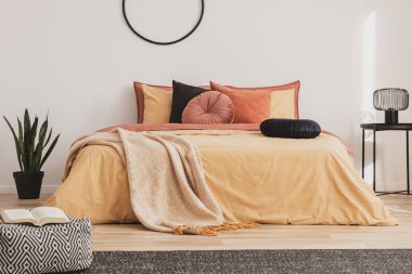 Sarı yorganın üzerinde siyah yuvarlak kadife yastık moda yatak odasının içinde kral yatağı büyüklüğünde.