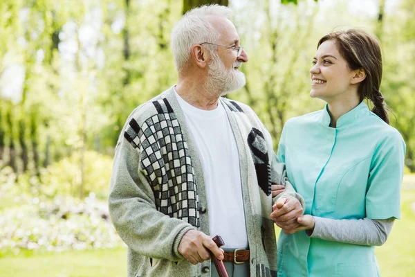 Homme âgé avec bénévole serviable dans le jardin de la maison de soins professionnels — Photo