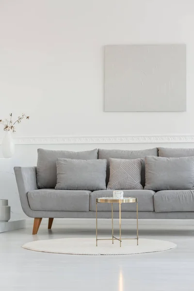 Pequeña mesa de centro elegante frente al sofá escandinavo largo en el interior luminoso habitación diaria —  Fotos de Stock