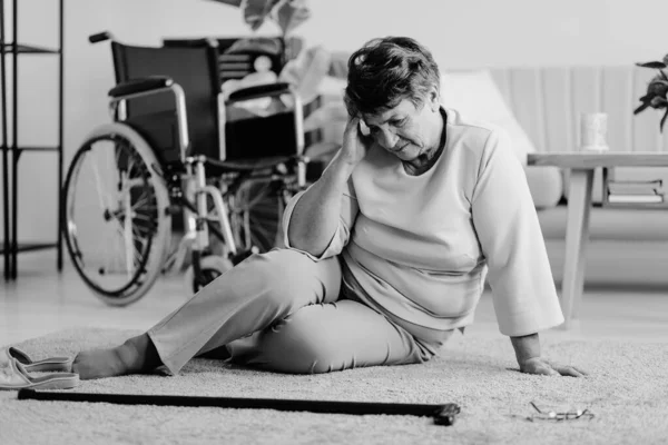 Sakit wanita tua cacat dengan sakit kepala di lantai dengan tongkat berjalan — Stok Foto