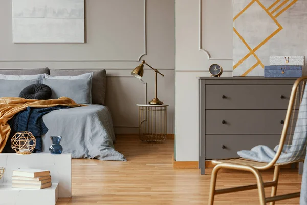 Trendy interno camera da letto con comò grigio e sedia dorata — Foto Stock