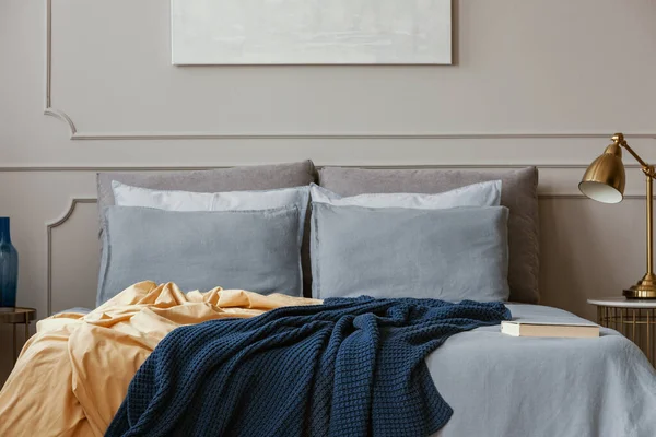Coperte blu scuro e arancio su comodo letto matrimoniale in camera da letto grigia elegante — Foto Stock