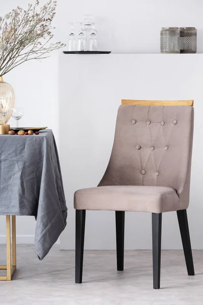 Cadeira elegante ao lado da mesa de jantar com toalha de mesa cinza no interior da sala de jantar na moda — Fotografia de Stock