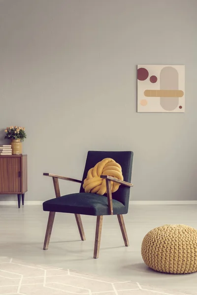 Żółta poduszka węzełkowa na modnym fotelu vintage w pustym pokoju — Zdjęcie stockowe