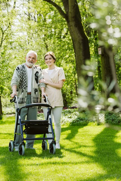 Verpleegster en patiënt in de tuin van modern bejaardentehuis met dagelijkse verzorging — Stockfoto