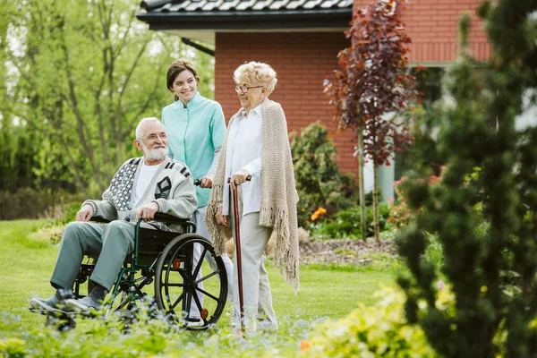 Старший мужчина на инвалидной коляске в саду дома престарелых — стоковое фото