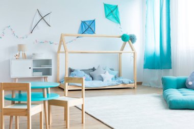 Çocukların yatak odasında mavi şilteli ve sandalyeli masalı ev yapımı mavi ve beyaz uçurtmalar.