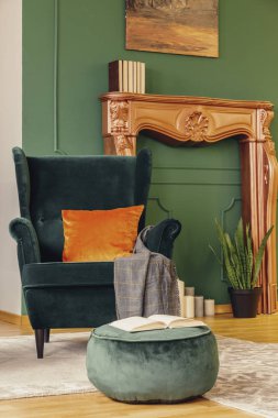 Moda oturma odasındaki yeşil pouf hakkında açık bir kitap.