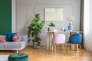 Parlak oturma odasında küçük yemek masasında Kadife pastel pembe ve benzinli mavi sandalyeler