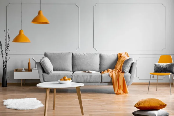 Lampada arancione sopra divano scandinavo grigio in interni moderni — Foto Stock