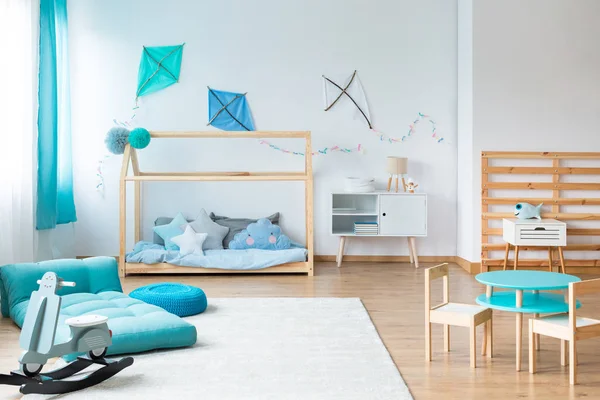 Cometas azules de bricolaje en la pared blanca vacía en el dormitorio de bebé escandinavo con futón y muebles de madera —  Fotos de Stock
