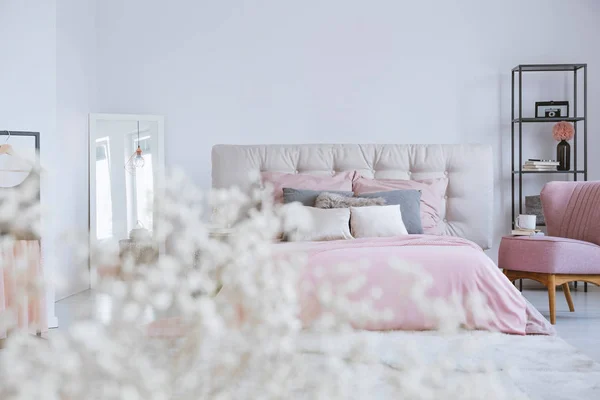 Пастельные постельные принадлежности на двуспальной кровати в стильном интерьере спальни с пустой белой стеной — стоковое фото