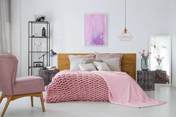 Розовое уютное шерстяное одеяло и одеяло на теплую двуспальную кровать в стильном интерьере спальни, абстрактная роспись на пустой стене — стоковое фото