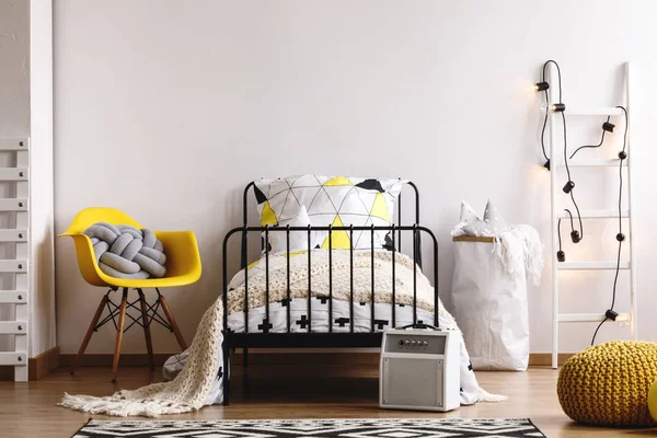 Копировать пространство на пустой белой стене в стильной спальне скандинавского ребенка с односпальной металлической кроватью, желтый стул и бумажный пакет с подушками — стоковое фото