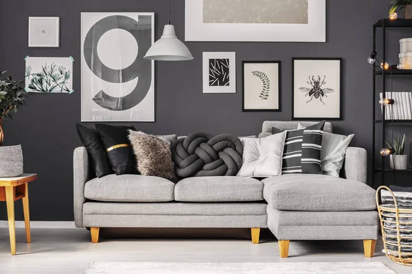 Almohadas grises y negras en cómodo sofá esquinero en la sala de estar escandinava de moda — Foto de Stock