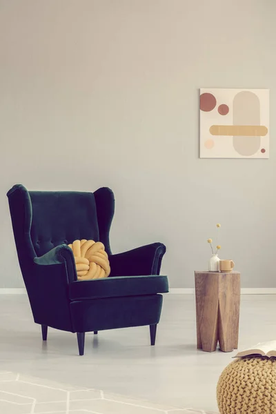 Крыло спинной кресло с желтой подушкой узел рядом со стильным деревянным журнальным столиком — стоковое фото