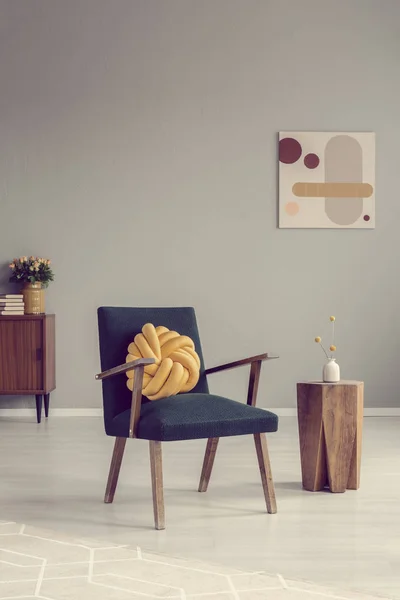 Żółta poduszka węzełkowa na modnym fotelu vintage w pustym pokoju — Zdjęcie stockowe