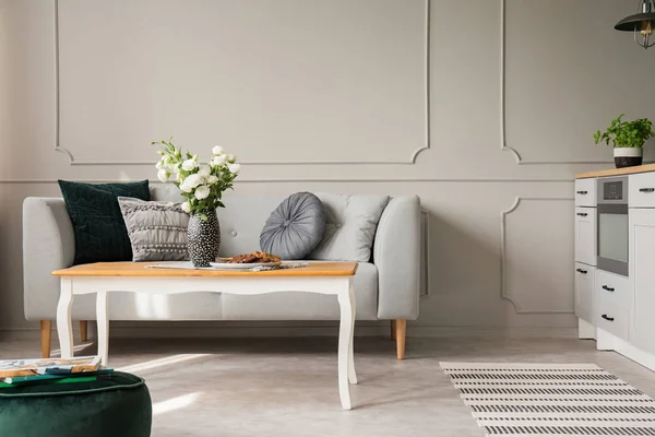 Elegante mesa de café na frente sofá moderno na sala de estar interior com parede cinza — Fotografia de Stock