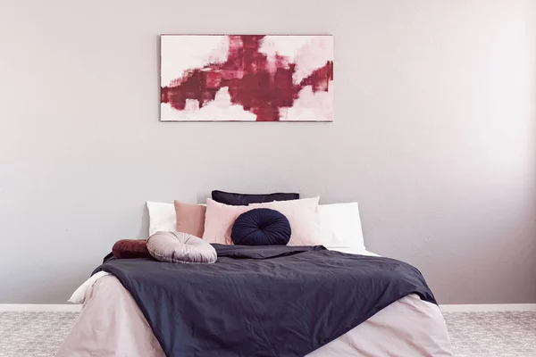 분홍색과 검은 색 침구와 킹 사이즈 침대 위의 추상 아마란스와 파스텔 핑크 페인팅 — 스톡 사진