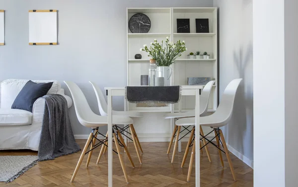 Blommor i vas på vitt matbord med fyra trendiga stolar i elegant vardagsrum — Stockfoto