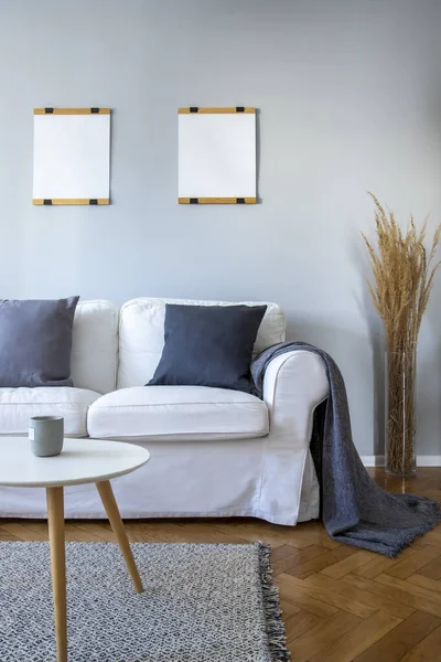 Šedé polštáře a přikrývka na bílé pohovce v malém obývacím pokoji — Stock fotografie