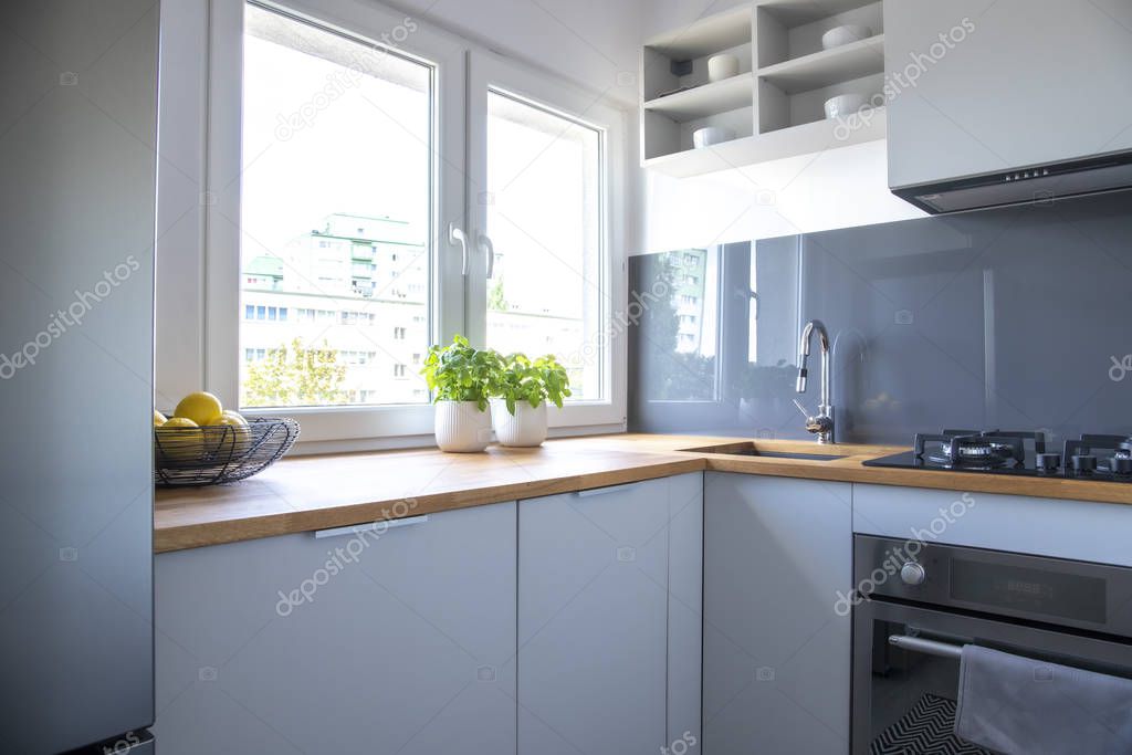 Herbs and lemons on wooden counter of small kitchen with white cupboards