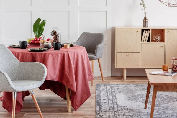 Elegantní jídelní stůl pokrytý zázvorovým ubrus v interiéru obývacího pokoje se stylovými židlemi — Stock fotografie