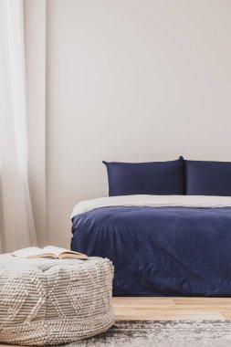 Boş yatak odası. İçinde mavi yatak odası ve pouf üzerine kitap var. Duvardaki boşluğu kopyala.