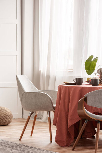 Living and dining room interior with grey couch and table covered with orange tablecloth