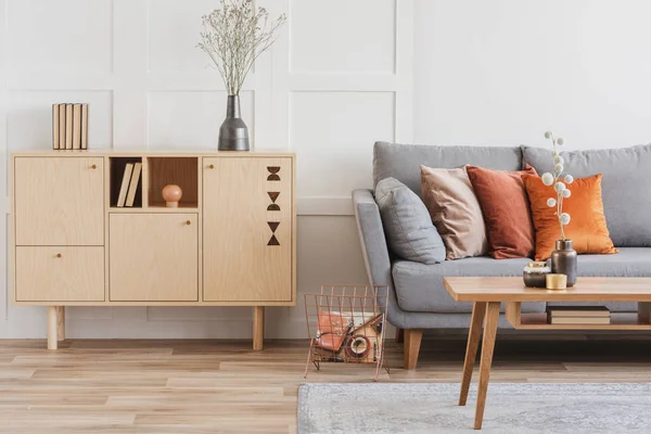 Mobili in legno e divano scandinavo grigio con cuscini in bellissimo soggiorno interno — Foto Stock