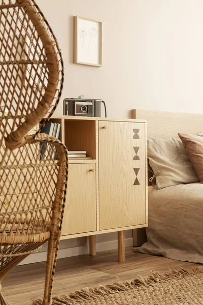 Cámara vintage en gabinete de madera al lado de la cama con cabecero de madera y ropa de cama beige —  Fotos de Stock