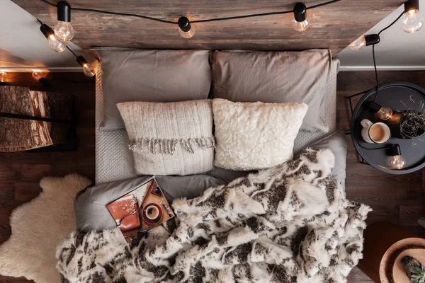 Vista superior da cama desfeita com travesseiros, cobertor quente e revista — Fotografia de Stock