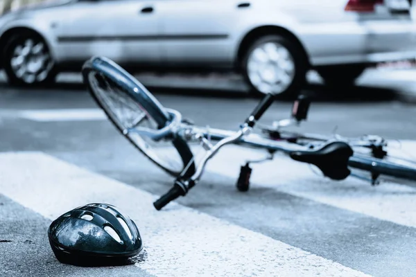 Broken helmet and bike on pedestrian area after terrible car crash — Stock Photo, Image