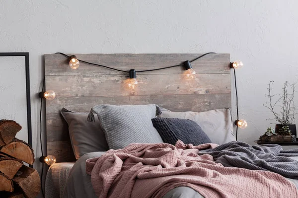 Wystrój sypialni świątecznej ze światłami i drewnem — Zdjęcie stockowe