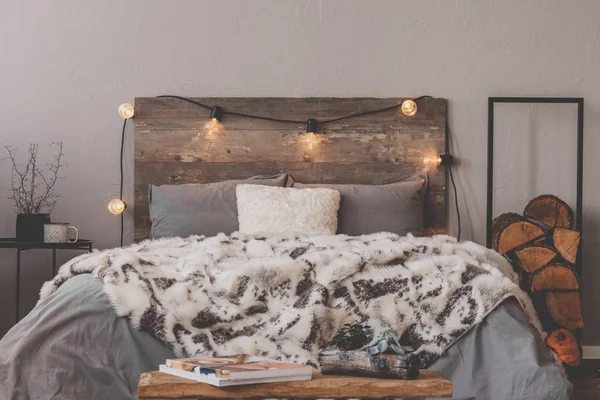 Sıcak yorgan, rahat bir yatak, kırsal bir yatak başlığı ve ışıklar. — Stok fotoğraf