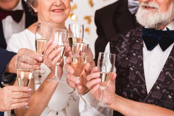 Äldre glada vänner skålar med champagne på nyårsafton — Stockfoto