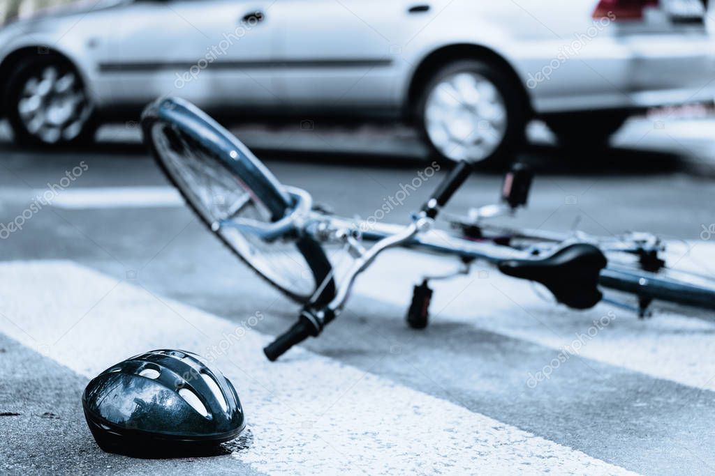 Broken helmet and bike on pedestrian area after terrible car crash