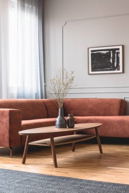 Zencefil renkli köşe kanepe önünde ahşap sehpa üzerinde şık koyu vazo kuru çiçekler